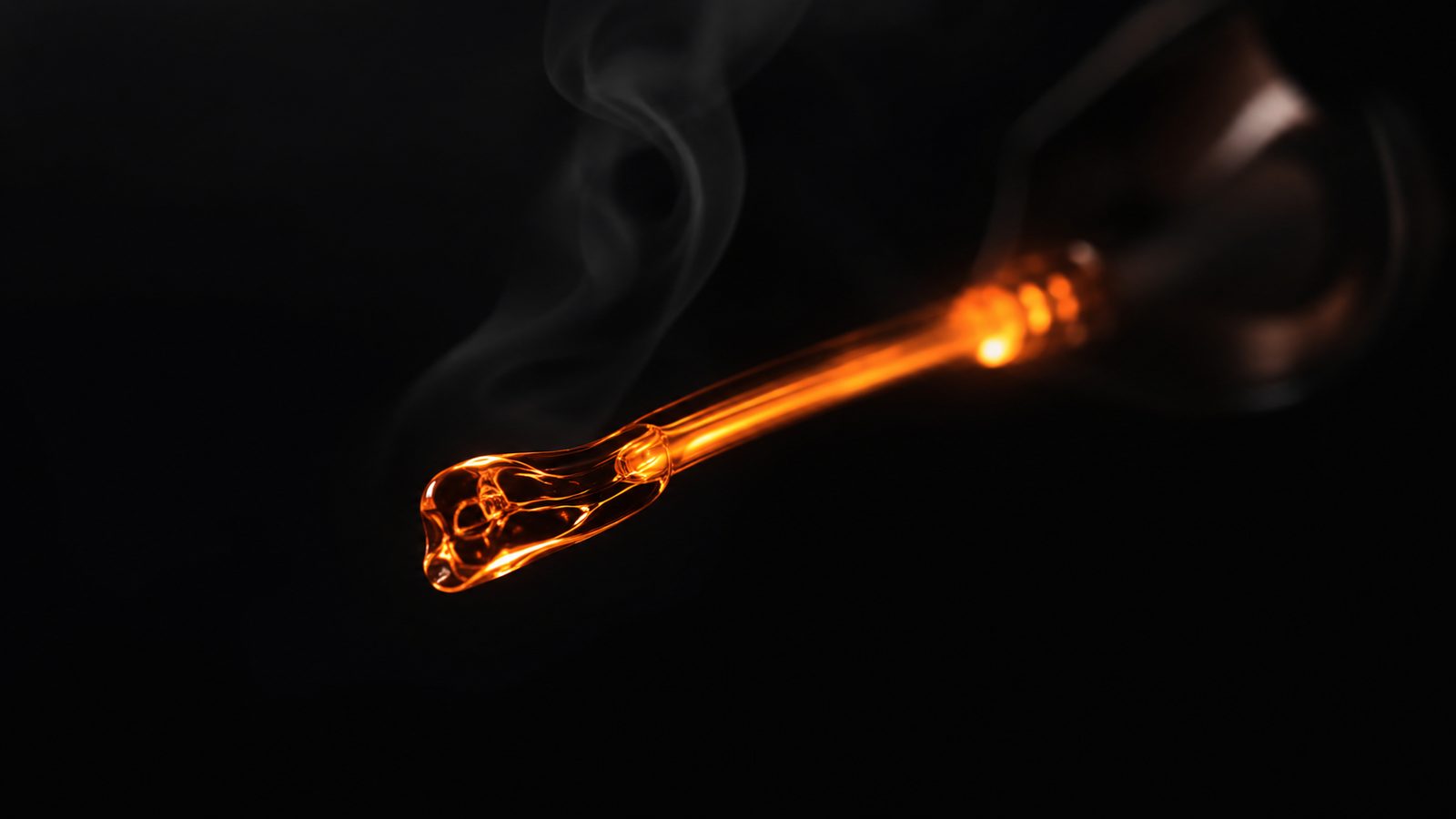 Molten glass filament glowing against darkness